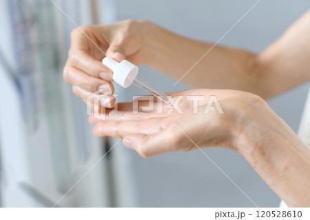 美容液を手に垂らす中年女性の手元 美容液を手に垂らす中年女性の手元 120528610