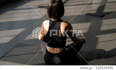 Mindful yoga. Zen practice. Unrecognizable woman sit lotus pose on mat enjoying meditation exercise breath gymnastic energy balance in gym fitness studio indoors. Mindful yoga. Zen practice. Unrecognizable woman sit lotus pose on mat enjoying meditation exercise breath gymnastic energy balance in gym fitness studio indoors. 120529436