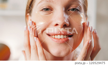 Skin breathe. Moisturizing face. Young smiling girl with natural makeup healthy fresh skin applying collagen hydrogel eye patches. Skin breathe. Moisturizing face. Young smiling girl with natural makeup healthy fresh skin applying collagen hydrogel eye patches. 120529475