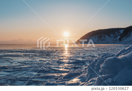 The sun sets over a frozen sea, casting a golden glow across the ice The sun sets over a frozen sea, casting a golden glow across the ice 120530627