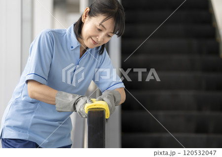 エスカレーターの手すりを拭くミドルの女性清掃スタッフ 120532047