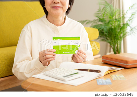 通帳を持って笑うミドル〜シニア女性と家計簿 通帳を持って笑うミドル〜シニア女性と家計簿 120532649