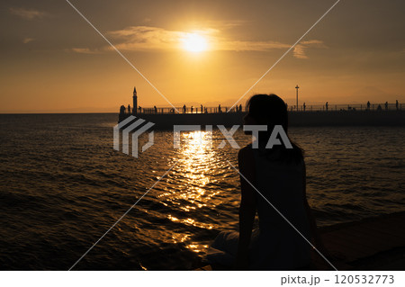 港で夕日を眺める女性 港で夕日を眺める女性 120532773