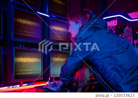 Asian woman wearing a black jacket hacking programming system and working with computer monitor display in dark office, Cyber security agency developing website cyber security, Monitoring Information 120533623