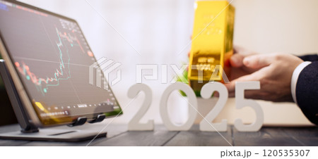 2025 Investment Trends: Businessman Holding Gold Bar with Digital Financial Charts and Market Indicators 120535307