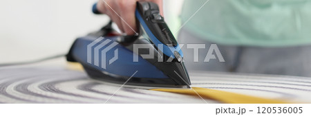 Male person irons yellow tie with hot steam in morning 120536005