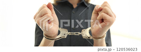 Female person with handcuffs on wrists in prison cell Female person with handcuffs on wrists in prison cell 120536023