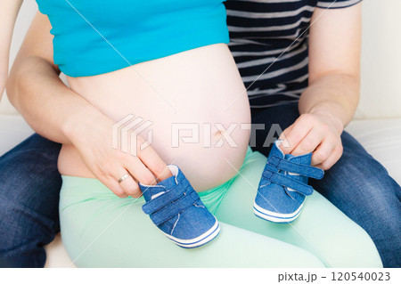 Couple expecting baby, man playing with little shoes 120540023