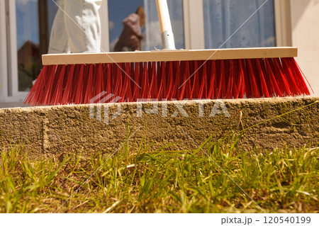 Person cleaning patio using brush broom 120540199