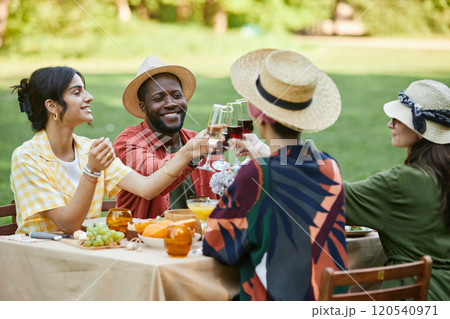 Group of friends enjoying picnic outdoors, sharing food and drinks in sunny park setting. Celebrating with cheerful faces, sitting around picnic table Group of friends enjoying picnic outdoors, sharing food and drinks in sunny park setting. Celebrating with cheerful faces, sitting around picnic table 120540971
