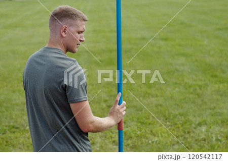 Man Preparing for Javelin Throw in Open Field 120542117