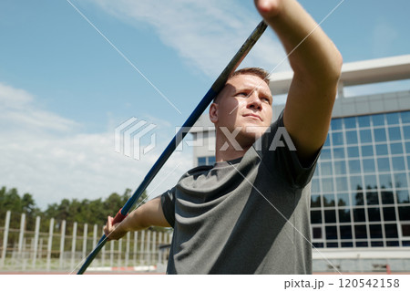 Holding Javelin at Athletic Track with Modern Building Background 120542158