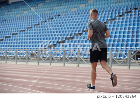Man Running Alone on Track in Empty Stadium Man Running Alone on Track in Empty Stadium 120542264