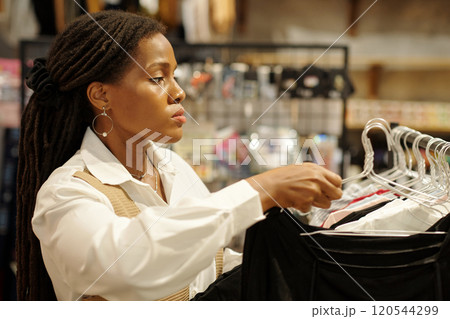 Woman Browsing Clothing Rack in Retail Store Woman Browsing Clothing Rack in Retail Store 120544299