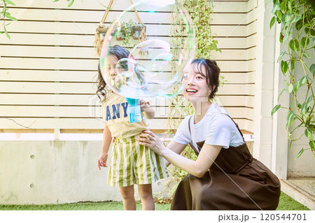 庭で電動シャボン玉を使って遊ぶ親子 120544701