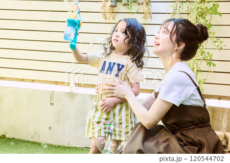 庭で電動シャボン玉を使って遊ぶ親子 120544702