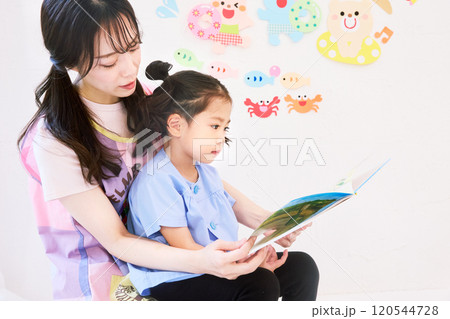 園児と絵本を読む保育士 120544728