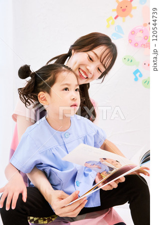 園児と絵本を読む保育士 120544739