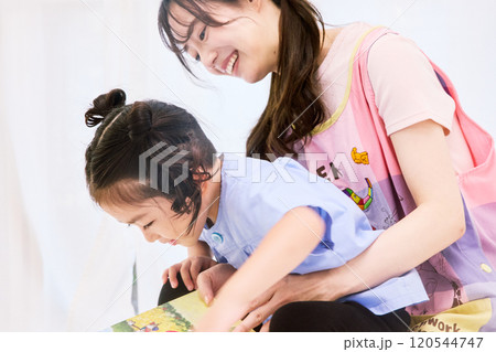 園児と絵本を読む保育士 120544747