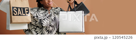 Smiling Woman Holding Shopping Bags While Bargain Hunting Smiling Woman Holding Shopping Bags While Bargain Hunting 120545226