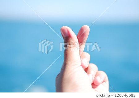 Hands forming a heart shape with the sea in the background. 120546083