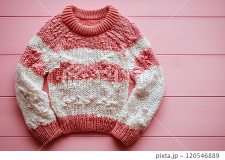 A pink and white striped knitted sweater with a cozy texture, displayed on a pink wooden background A pink and white striped knitted sweater with a cozy texture, displayed on a pink wooden background 120546889