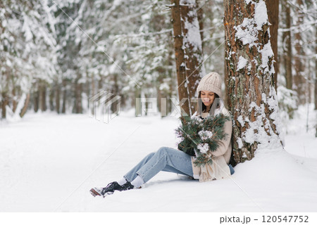 Young woman is sitting in the snow with bouquet of flowers in her lap 120547752