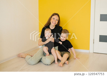 Young happy woman sits on the floor with her two children. Scene is happy and loving Young happy woman sits on the floor with her two children. Scene is happy and loving 120547753