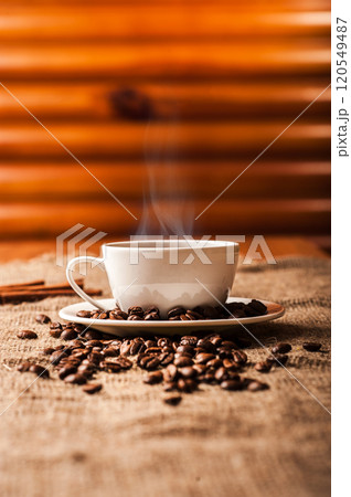 A delicious freshly brewed cup of coffee.A cup of freshly made coffee smokes on a plate, cinnamon. A delicious freshly brewed cup of coffee.A cup of freshly made coffee smokes on a plate, cinnamon. 120549487