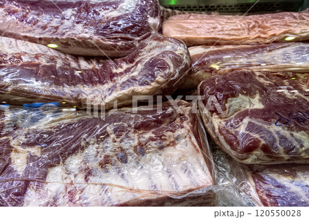 Large pieces of raw chilled meat vacuum packed in butcher shop display case. Large pieces of raw chilled meat vacuum packed in butcher shop display case. 120550028