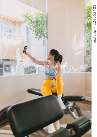 Woman in yellow blue fitness outfits taking selfie while resting from training. 120552483
