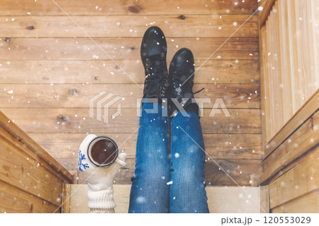 A girl in the boots with an iron mug of coffee on the terrace of a wooden house. concept 120553029