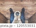 A girl in the boots with an iron mug of coffee on the terrace of a wooden house. concept 120553031