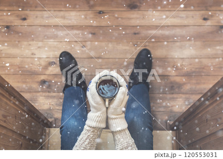 A girl in the boots with an iron mug of coffee on the terrace of a wooden house. concept 120553031