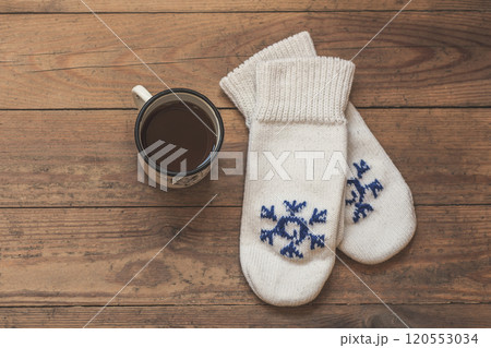 iron mug with coffee and knitted mittens on the wooden floor. Winter concept iron mug with coffee and knitted mittens on the wooden floor. Winter concept 120553034