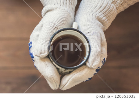 female hands  with an iron mug of coffee on the terrace of a wooden house. concept 120553035