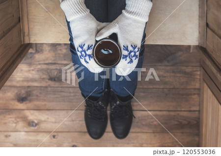 A girl in the boots with an iron mug of coffee on the terrace of a wooden house. concept 120553036