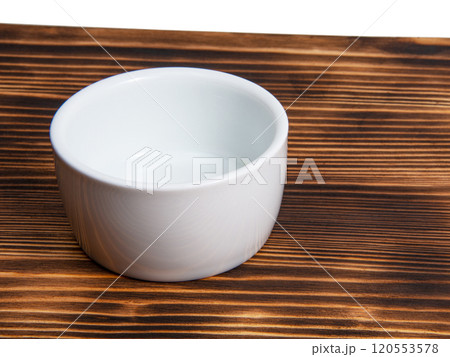Empty white dish on dark wooden desk 120553578