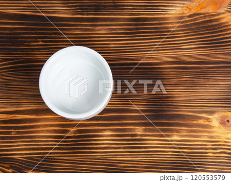 Empty white dish on dark wooden desk 120553579