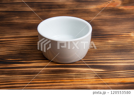 Empty white dish on dark wooden desk 120553580
