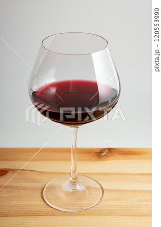 Elegant wineglass with red wine on bright vintage wooden background 120553990