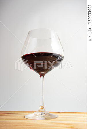 Elegant wineglass with red wine on bright vintage wooden background 120553991