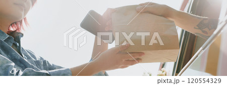 Website banner with low angle shot of unrecognizable food truck worker giving bag with order to female client 120554329