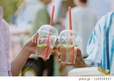 Medium close up of transparent plastic cups with sparkling craft lemonade in unrecognizable peoples hands Medium close up of transparent plastic cups with sparkling craft lemonade in unrecognizable peoples hands 120554337