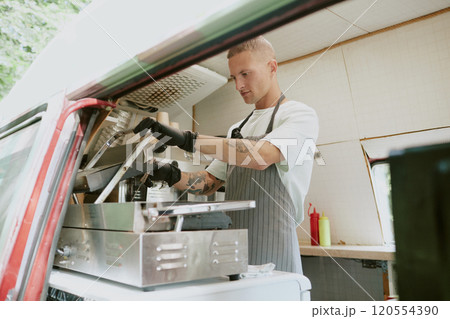 Low angle shot of Caucasian talented chef preparing order on grill in food truck Low angle shot of Caucasian talented chef preparing order on grill in food truck 120554390