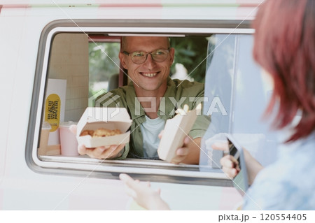 Medium close up of happy and smiling cook of food truck holding box of nuggets and french fries Medium close up of happy and smiling cook of food truck holding box of nuggets and french fries 120554405