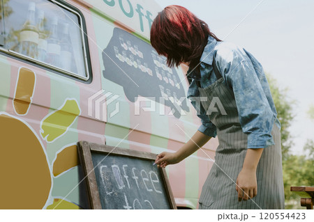Low angle shot of unrecognizable female worker in stripped apron writing down coffee menu on blackboard Low angle shot of unrecognizable female worker in stripped apron writing down coffee menu on blackboard 120554423
