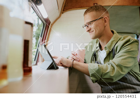 Smiling Caucasian worker of food truck texting in social network while having break at work Smiling Caucasian worker of food truck texting in social network while having break at work 120554431