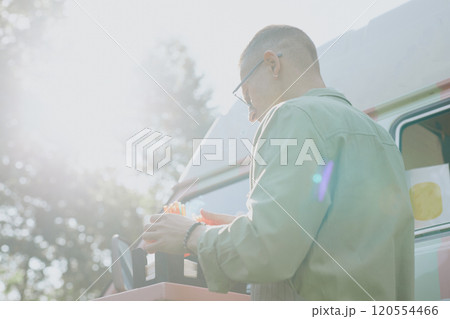 Low angle shot of unrecognizable man adjusting multicolored straws in plastic bow on table, he illumined with warm sunrays Low angle shot of unrecognizable man adjusting multicolored straws in plastic bow on table, he illumined with warm sunrays 120554466
