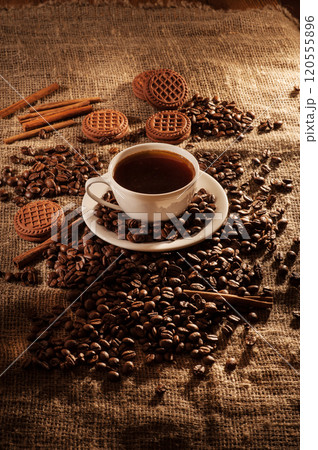 Coffee beans and a cup of coffee.Cup glass of coffee with smoke and coffee beans on old wooden backgroundth smoke and coffee beans on old wooden background 120555896